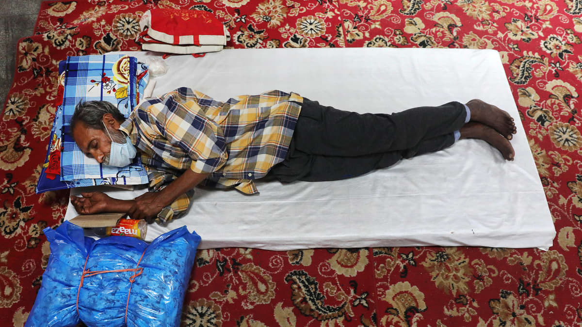 Kuvassa mies makaa patjalla leposuojassa Intian Delhissä.