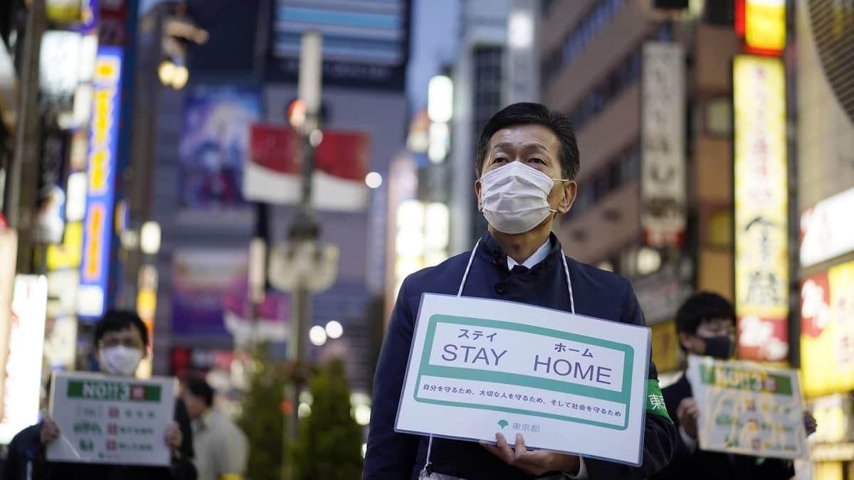 Japanin hallituksen työntekijät pitelivät pysy kotona -kylttejä Tokiossa 17. huhtikuuta.