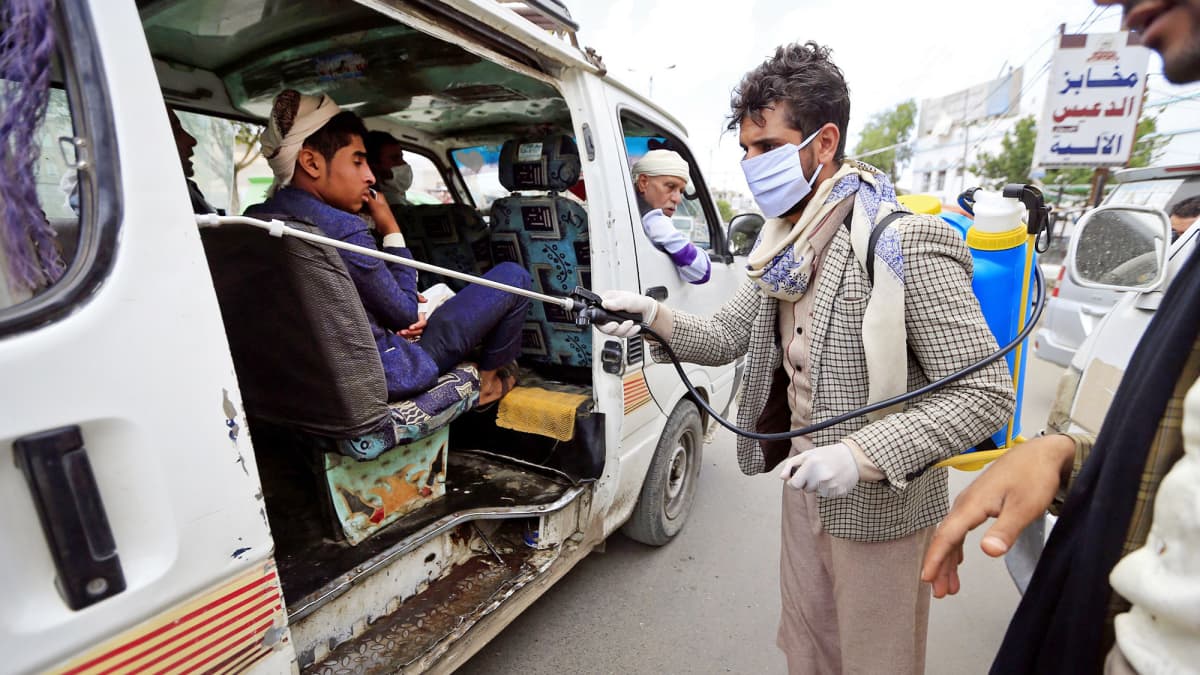 Vapaaehtoistyöntekijä desinfioi julkisessa liikenteessä käytettävää tila-autoa Jemenin Sanaassa.