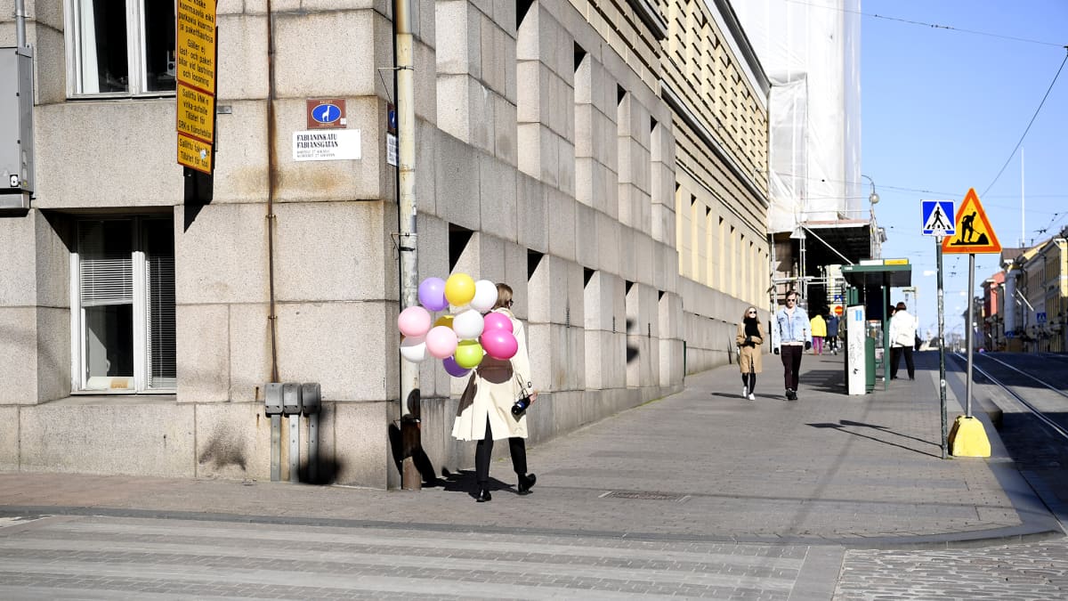 Nainen kävelee ilmapallokimpun kanssa Aleksanterinkadulla Helsingissä.
