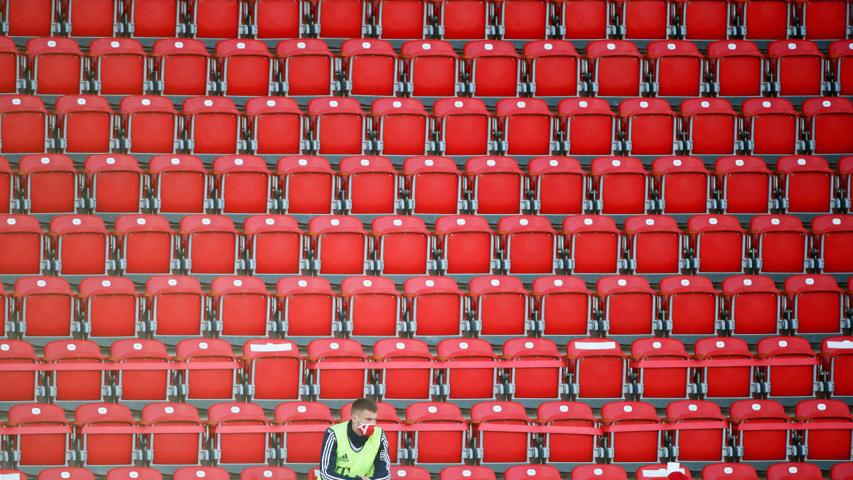 Vaihtopelaaja istuu yksin tyhjässä katsomossa jalkapallo-ottelussa Berliinissä.