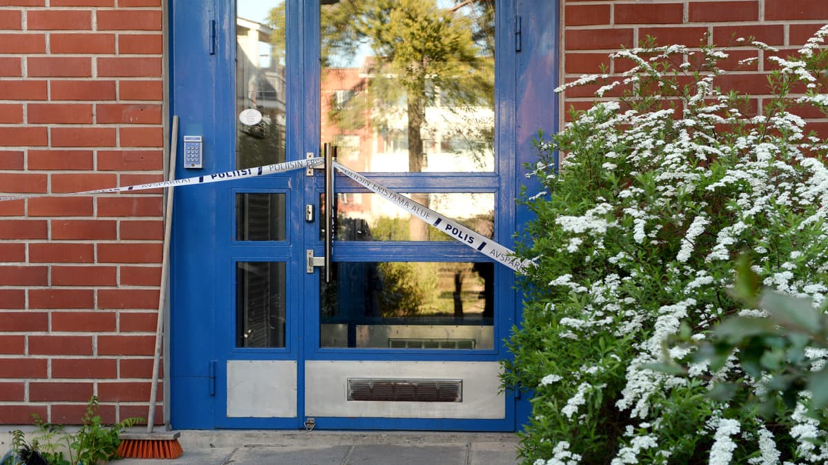 Poliisin sulkunauhaa kerrostalon alaovessa Espoon Mäkkylässä tiistaina 26. toukokuuta.