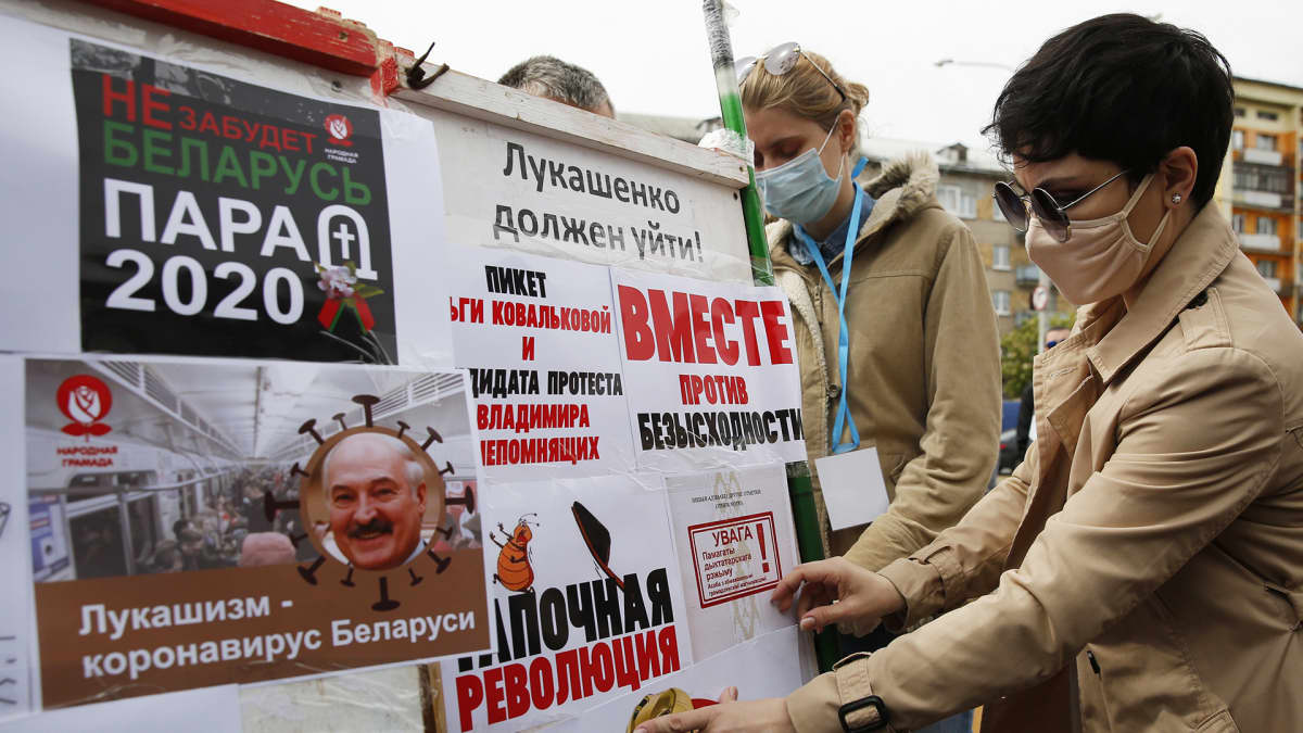 Opposition kannattajat liimaavat julisteita Valko-Venäjällä