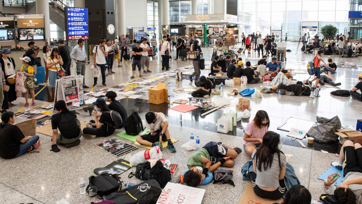 Kuvassa mielenosoittajat ovat vallanneet Hong Kongin kansainvälisen lentokentän aulan istumalla alueella tavarat levitettyinä.