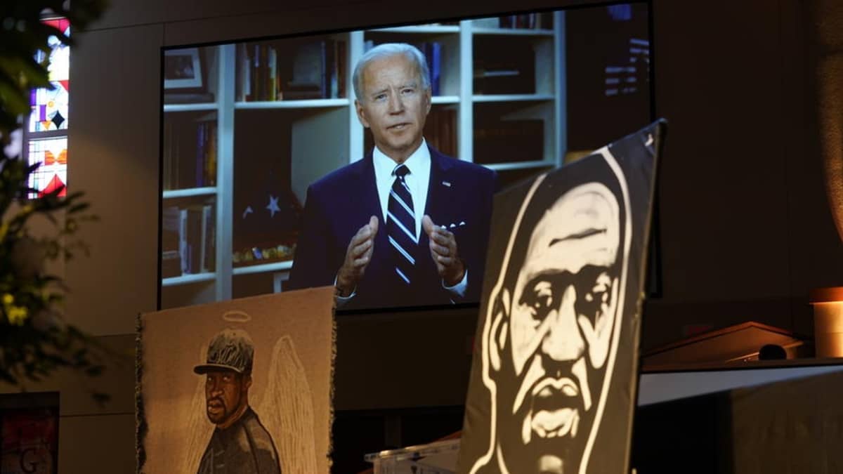 Kuvassa Joe Biden. Hänen edessään on kuva George Floydista. 