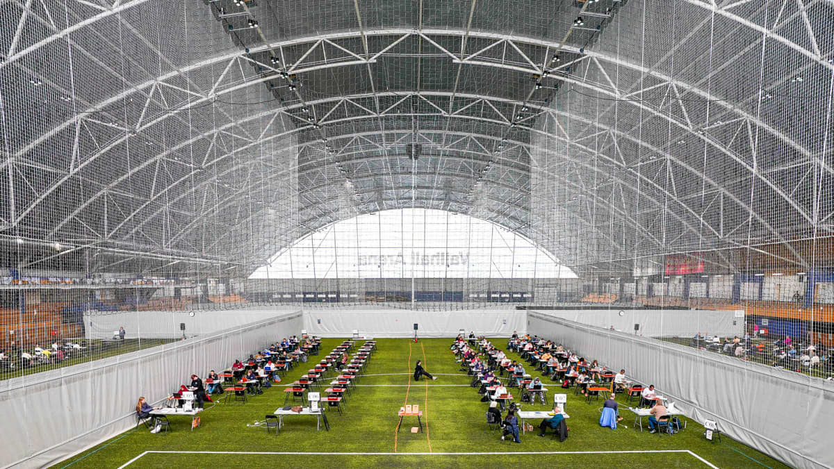 Kuvassa norjalaiset opiskelijat tekevät lukukauden päättökoetta väljästi isossa urheiluhallissa.