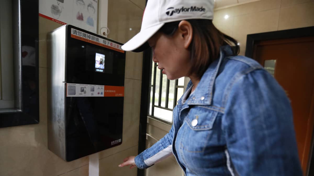 Nainen käyttää wc-paperoiautomaattia Pekingissä