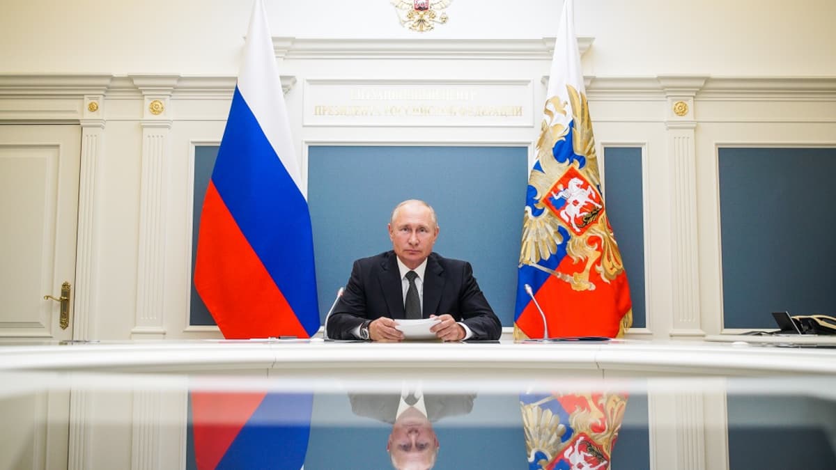 Putin pöydän ääressä. Hänen kuvansa heijastuu pöydän kiiltävältä pinnalta.