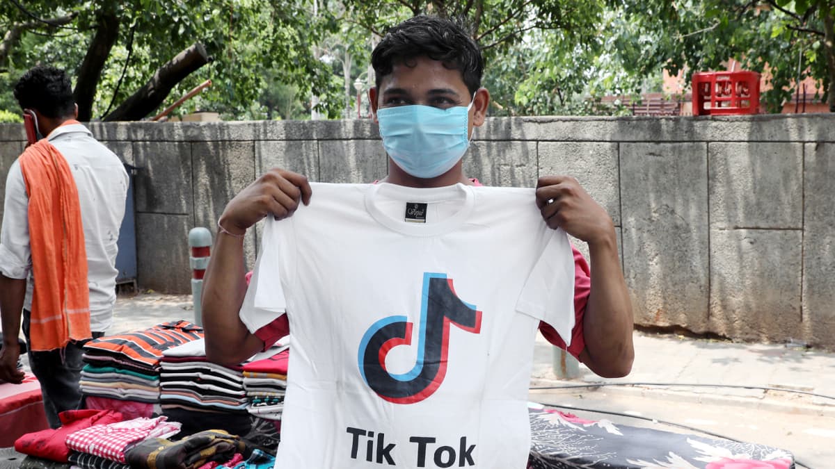 Intialainen paitakauppias esittelee Tiktokin logolla koristeltua t-paitaa New Delhissä.