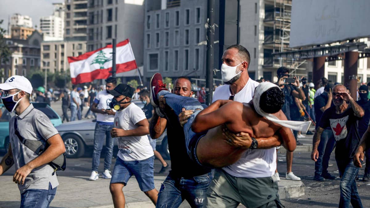 Mielenosoittaja kantaa haavoittunutta toveriaan turvaan Beirutin mellakoissa 8.8.2020.