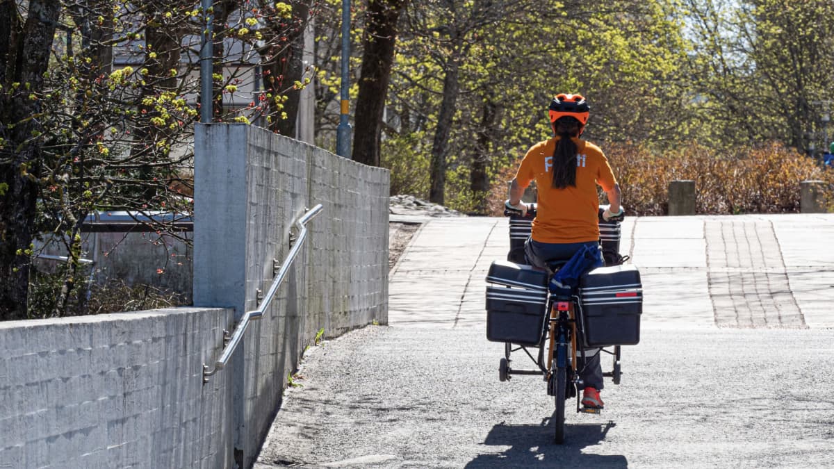 Postinjakelija jakaa postia polkupyörällä.
