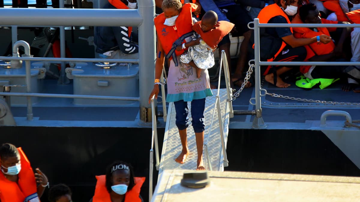 Siirtolainen ja hänen lapsensa rantautuu Maltalaisen laivan kannelta. 