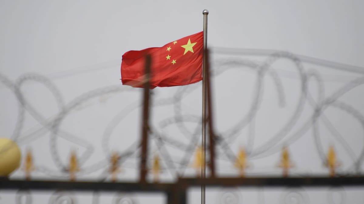 Kuvassa on Kiinan lippu piikkilanka-aidan takana.