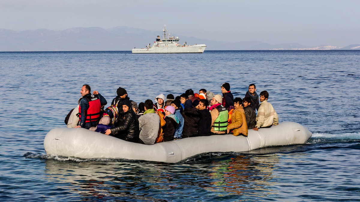 Kuvassa on Frontexin alus ja etualalla pakolaisia.