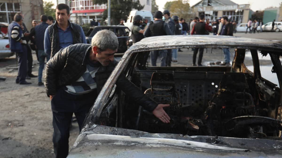 Mies katsastaa tuhoja Bardan kaupungin keskustassa tuhoutuneen auton vieressä.