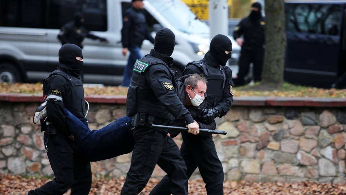 Mellakkapoliisit kantavat miestä mielenosoituksen yhteydessä Minskissä.
