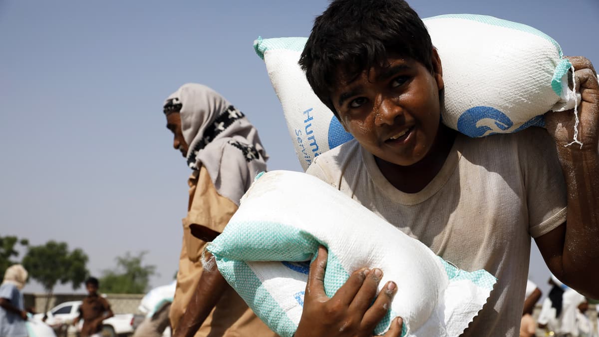 Jemeniläispoika kantaa ruokasäkkejä Hajjahissa Jemenissä syyskuussa 2020.