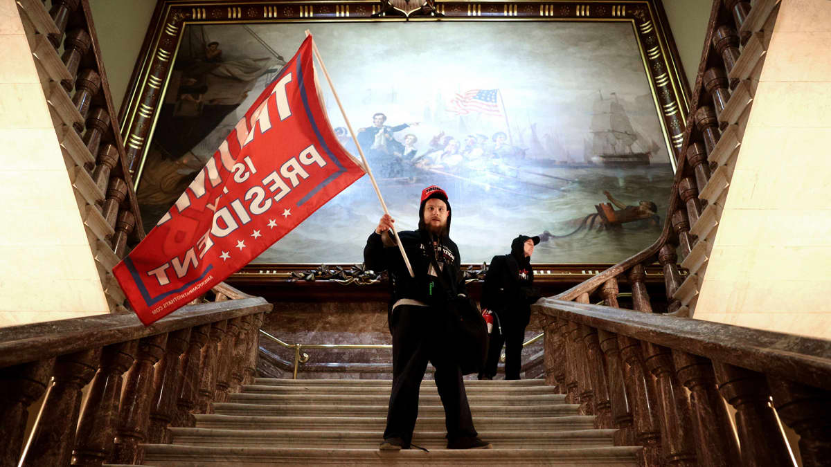 Mielenosoittaja heiluttaa lippua Yhdysvaltain kongressitalossa Washington DC:ssä.