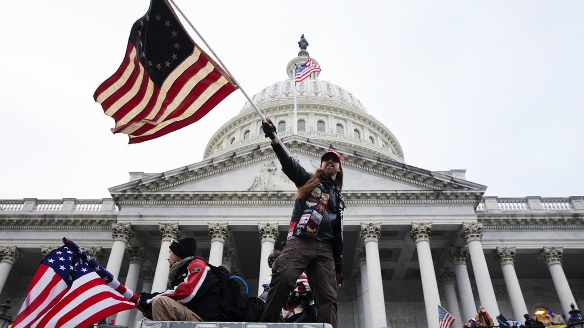 Mielenosoittaja heiluttaa lippua Yhdysvaltain kongressitalon edessä Washington DC:ssä.