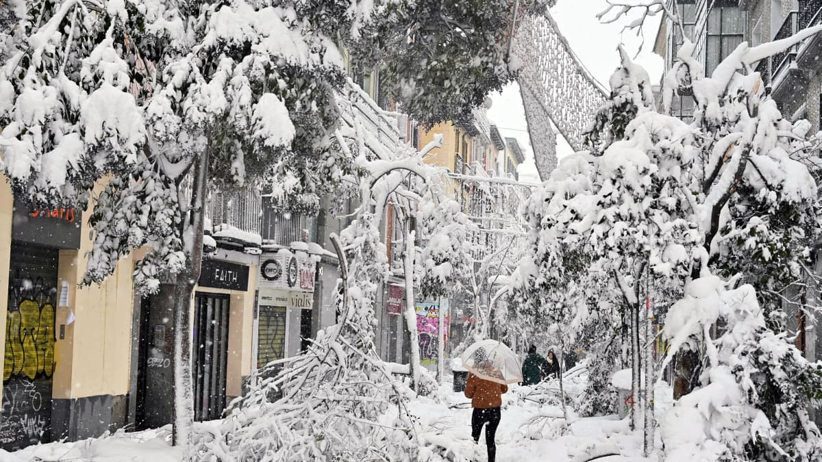 Ihmiset kahlaavat lumihangessa kaupungin kadulla.