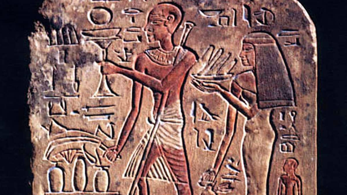 Egyotiläinen kivikaiverrus, jossa on lasia ja vatia pitelevät nainen ja mies. Miehen toinen jalka on kuihtunut, ja hänellä on sauva. 