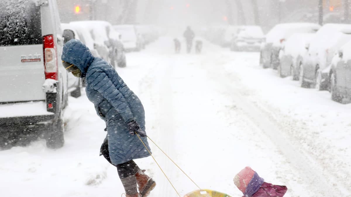 Nainen vetää lasta pulkassa lumimyrskyn keskellä New Yorkissa.