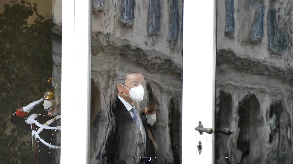 Mario Draghi ikkunalasin takana hengityssuoja kasvoillaan.