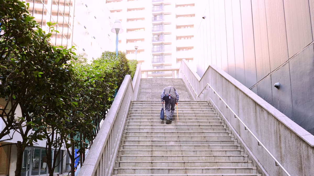 Vanhus kävelee ylös rappusia Shibuyassa, Tokiossa.