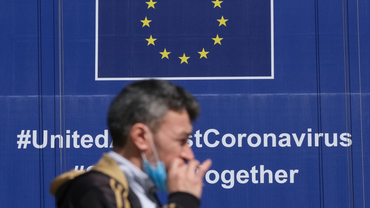 Mies kävelee EU-julisteen ohi, jossa kerrotaan yhteistyöstä koronakriisissä.