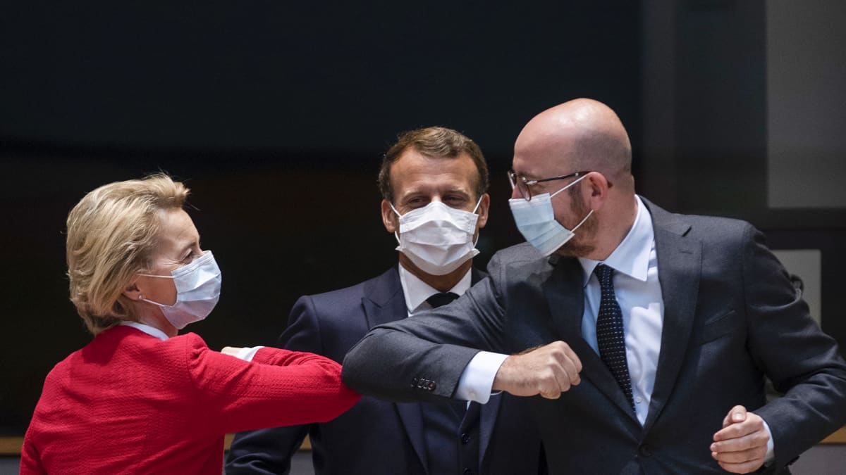 Ursula von der Leyen ja Charles Michel kyynärpäätervehtivät ja Emmanuel Macron katsoo taaempana.