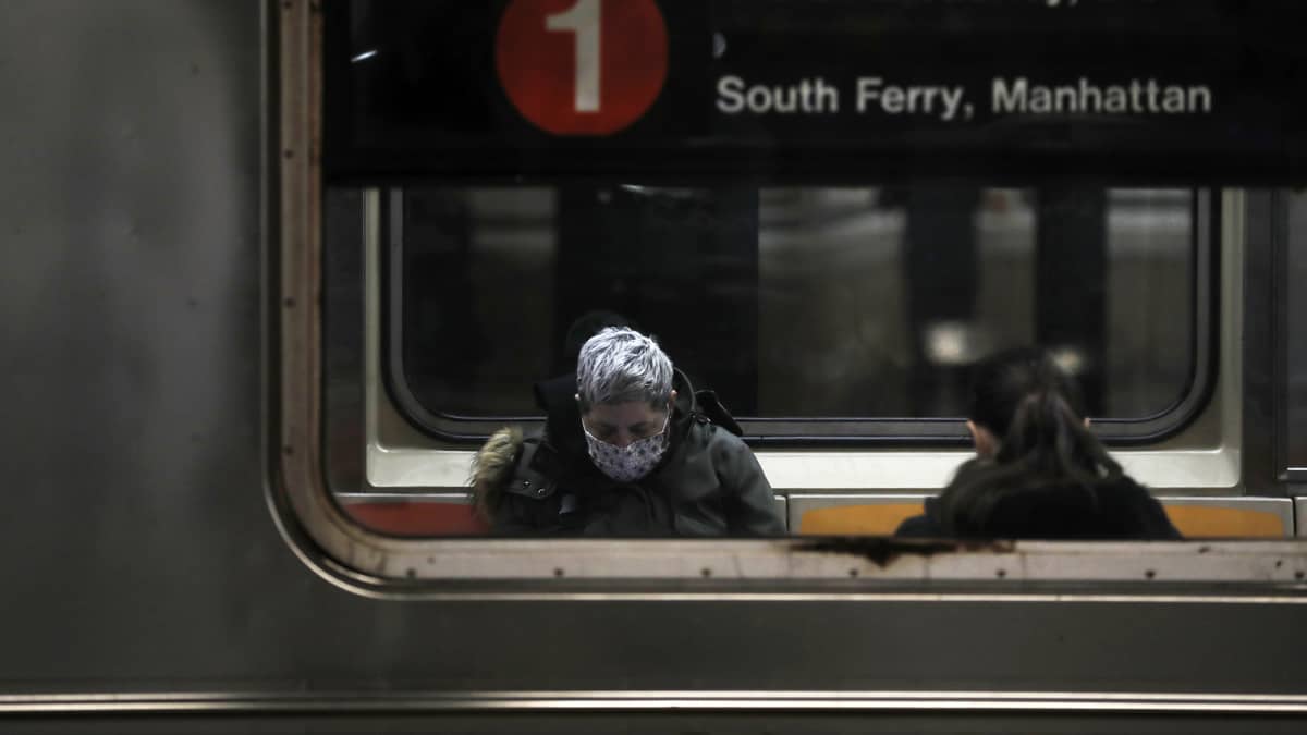Kasvomaskiin pukeutunut matkustaja New Yorkin metrossa.