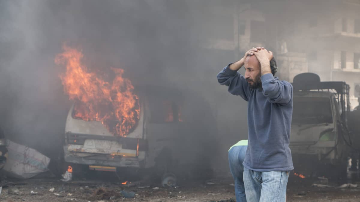 Mies seuraa järkyttyneenä kun talo palaa Aleppossa.