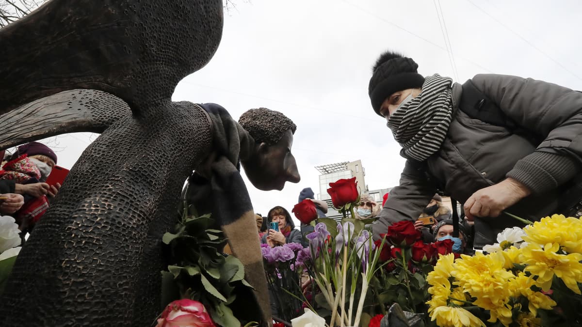 Nainen laittaa kukkia venäläisen muotoilijan Roman Shustrovin patsaan eteen Pietarissa, Venäjällä.