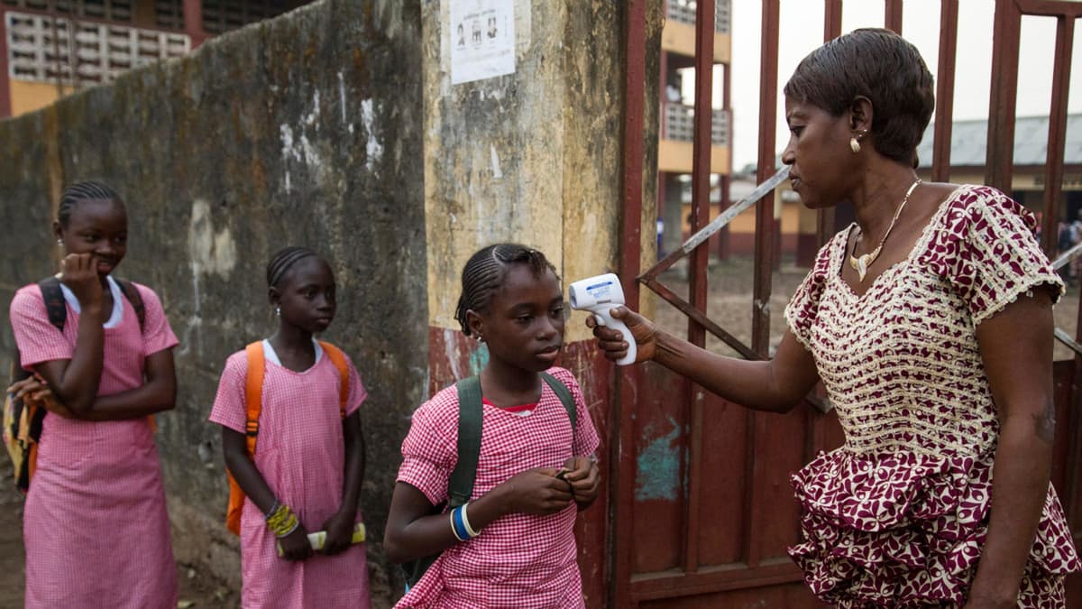 Lapsilta mitattiin lämpö koulun portilla tammikuussa 2015, kun koulut avautuivat pitkän sulun jälkeen. Kuva on otettu Guinean pääkaupungissa Conakryssa edellisen ebolaepidemian aikana.