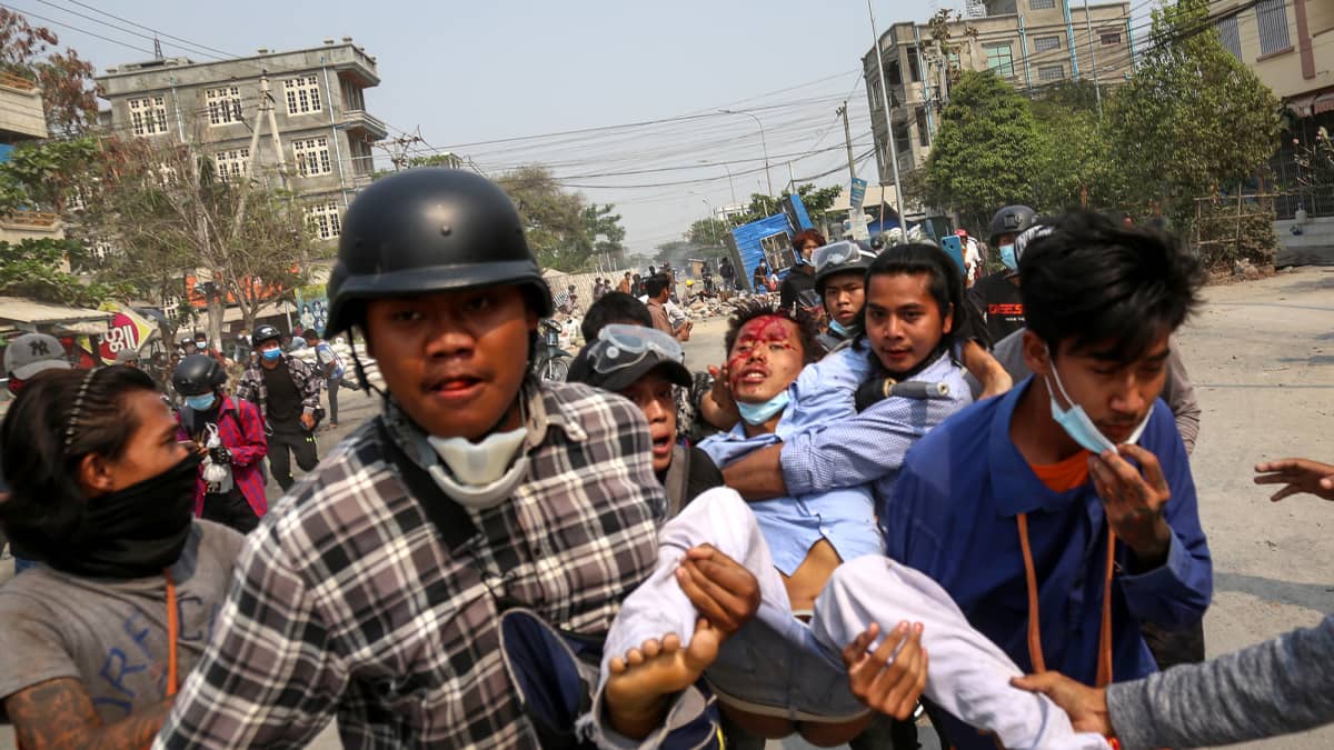 Mielenosoittajat kantavat haavoittunutta henkilöä pois mielenosoituksesta.