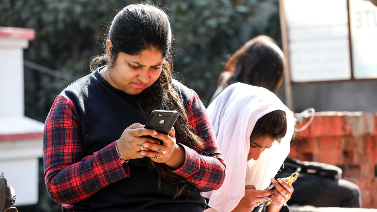 Intialaiset opiskelijat älypuhelimien kanssa internetissä.