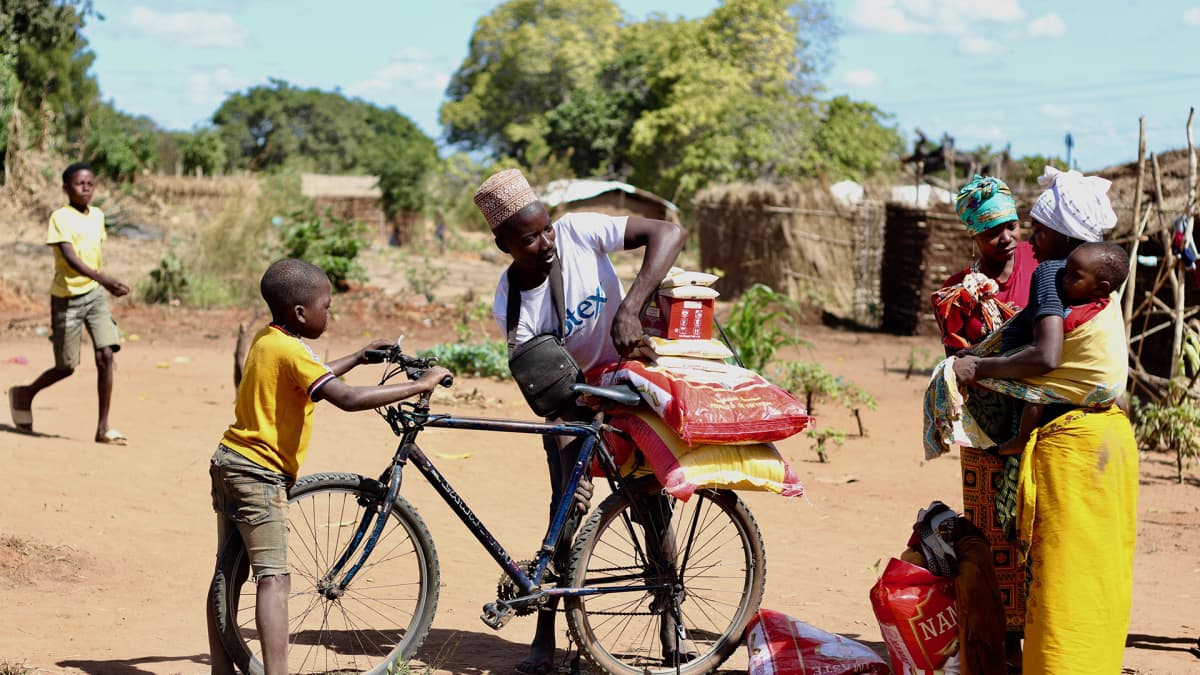 Mies lastaa juuri saamansa ruoka-apua pyörän selkään lähellä Montepuezin kaupunkia Cabo Delgadossa. 