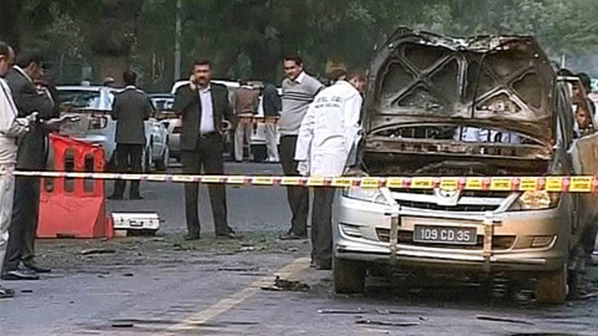 Poliisit ja rikospaikkatutkijat tutkivat pommin tuhoamaa autoa Israelin lähetystön edustalla.