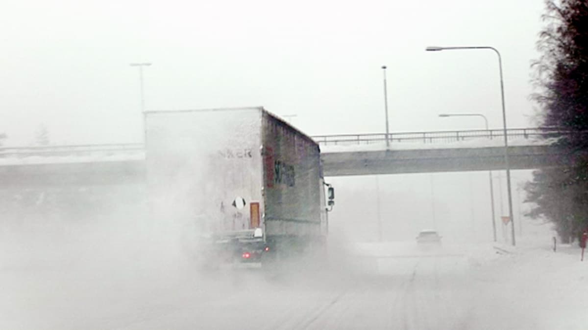 Autoja liikenteessä moottoritiellä lumisateessa.