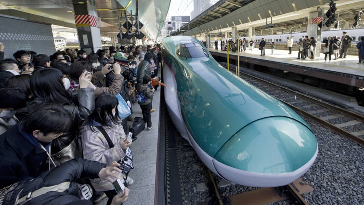 Uusimmasta Hayabusa-luotijunasta innostunut yleisö  katsomassa Tokion asemalla junan saapumista