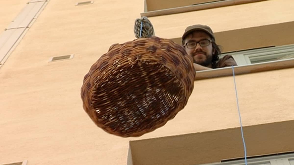Mikko Kjellberg laskee kotinsa ikkunasta ruokakoria kadulle narun avulla.