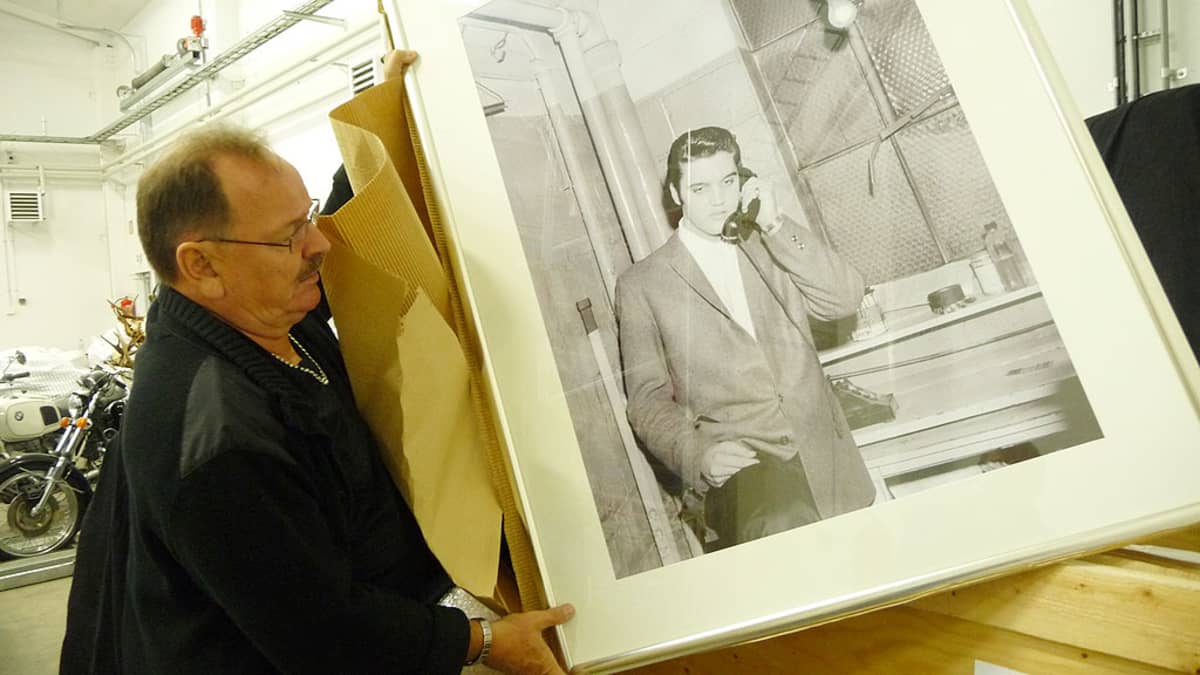 Kuvassa Kar Lindroos pitää kädessään kehystettyä valokuvaa Elviksestä