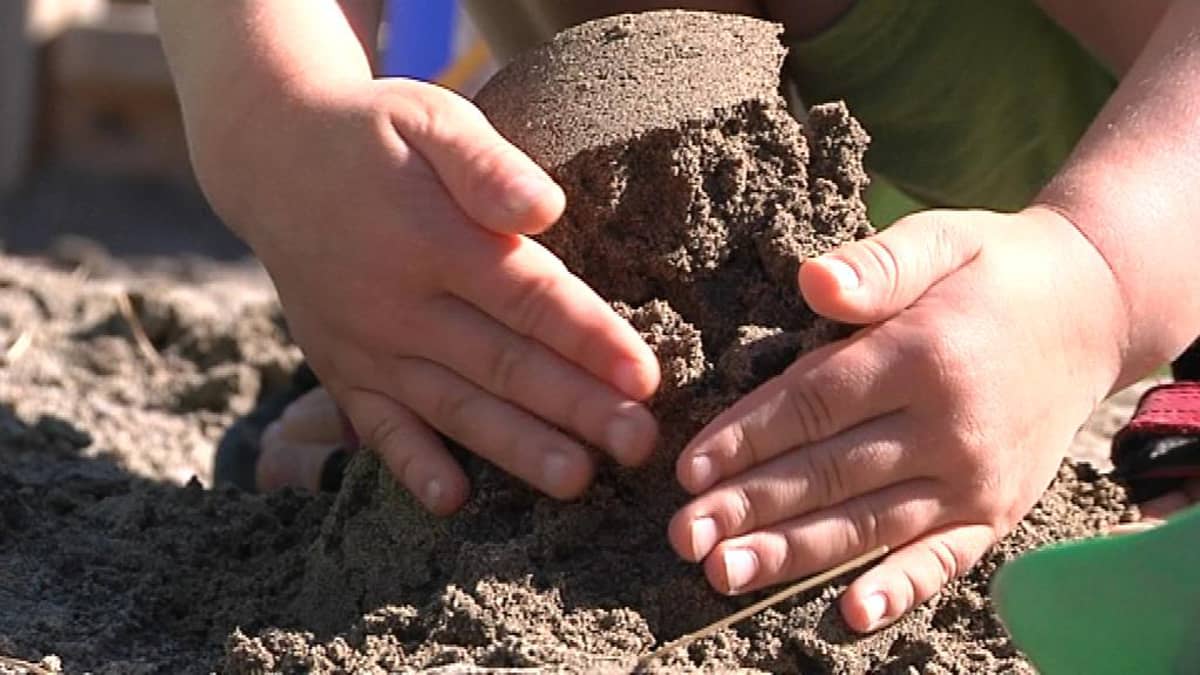 Lapsen kädet tekemässä hiekkakakkua