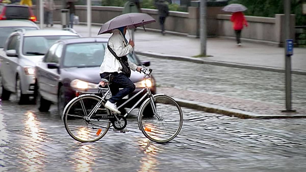 Pyöräilijä ylittää kadun sateessa
