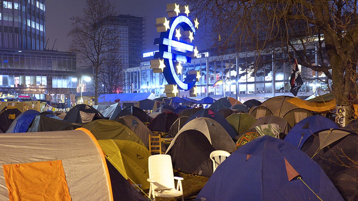Suuri euro-kyltti ja Occupy-liikkeen mielenosoittajien telttoja Euroopan keskuspankin rakennuksen edustalla.