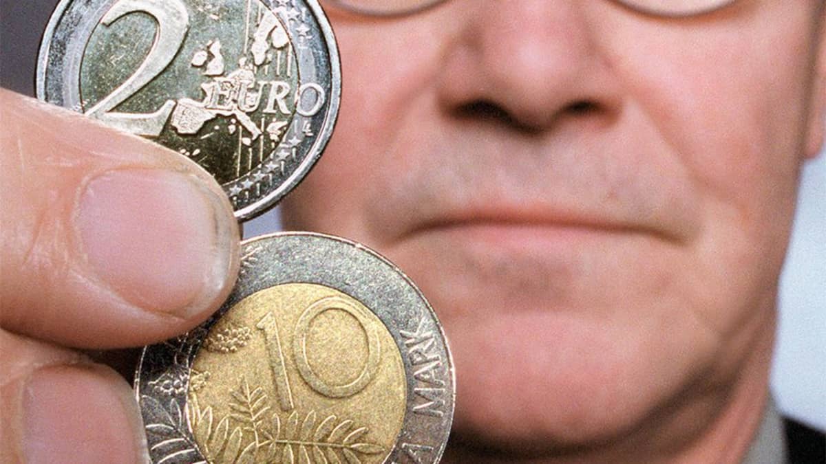 Mies pitelee kahden euron ja kymmenen markan kolikoita.
