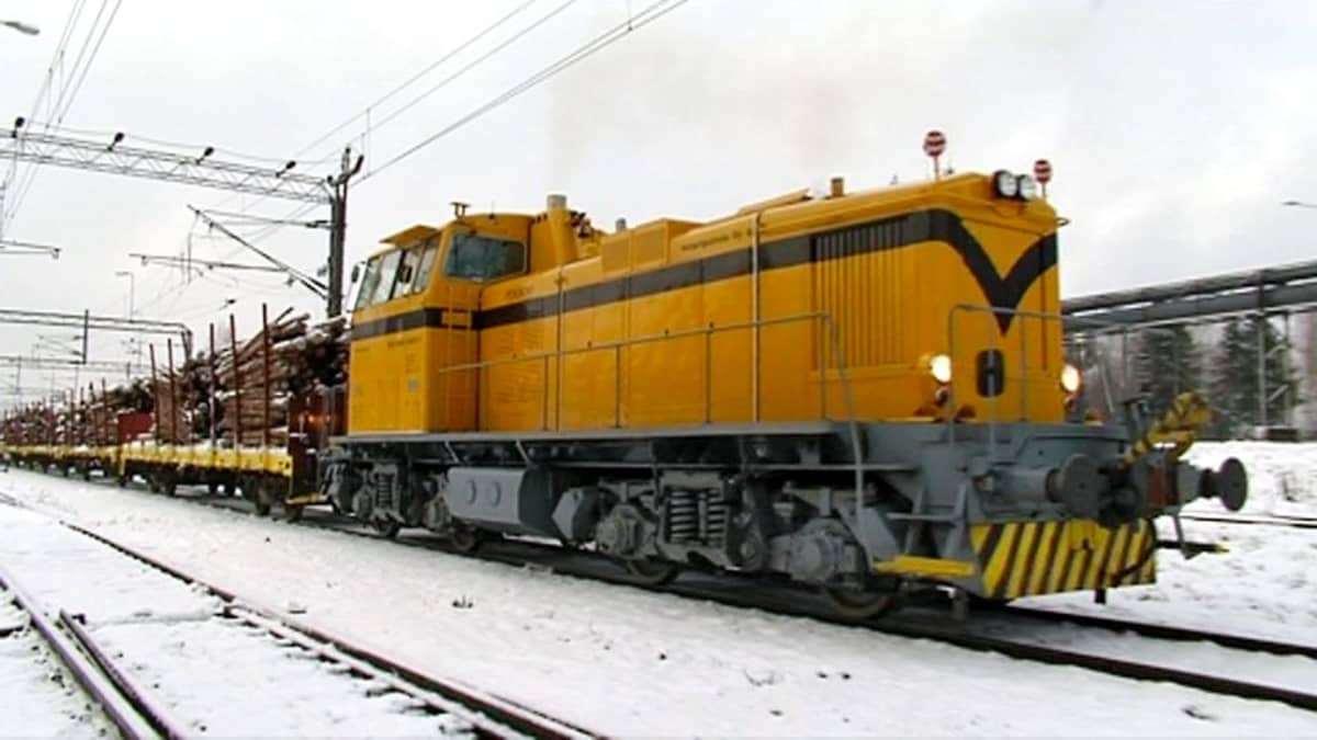 Tavarajunan keltainen veturiosa vetää puukuormaa.