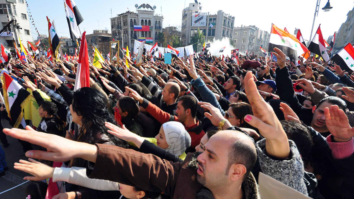 Presidentti Bashar al-Assadin puolesta aukiolle kokoontuneet mielenosoittajat ovat nostaneet oikean kätensä viistosti ilmaan.