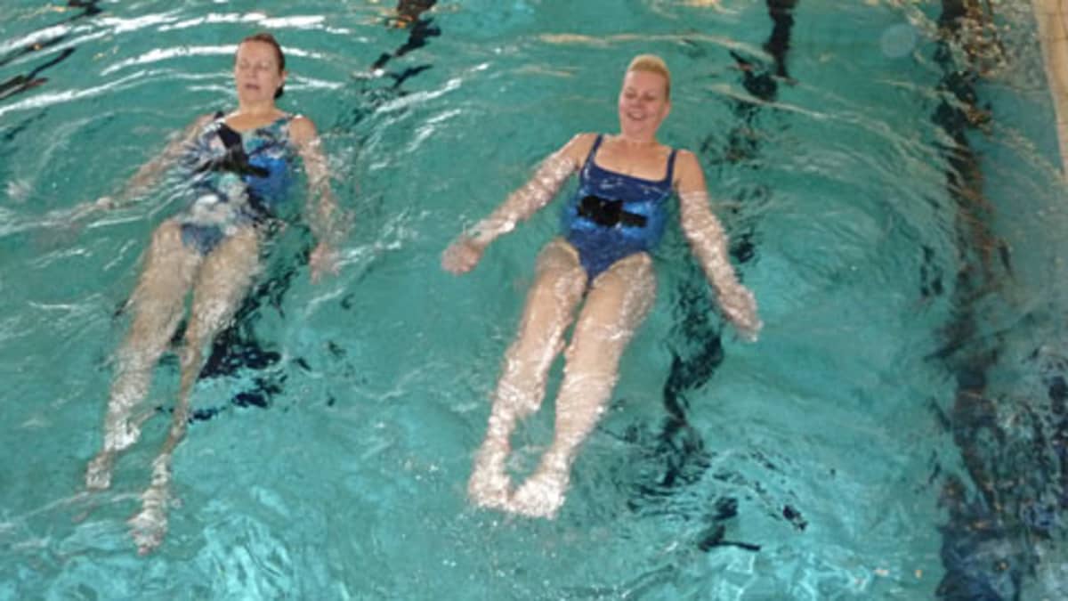 Kuvssa Ritva Björkbacka ja Hanna-Maija Jokela harjoittavat vatsalihaksia vesijuoksuvyön avulla. 