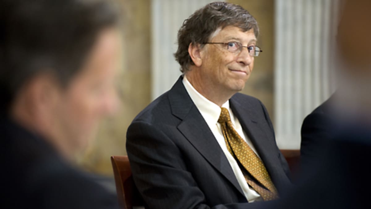 Bill Gates hymyilee kahden etualalla olevan epäselvän ihmishahmon välistä.